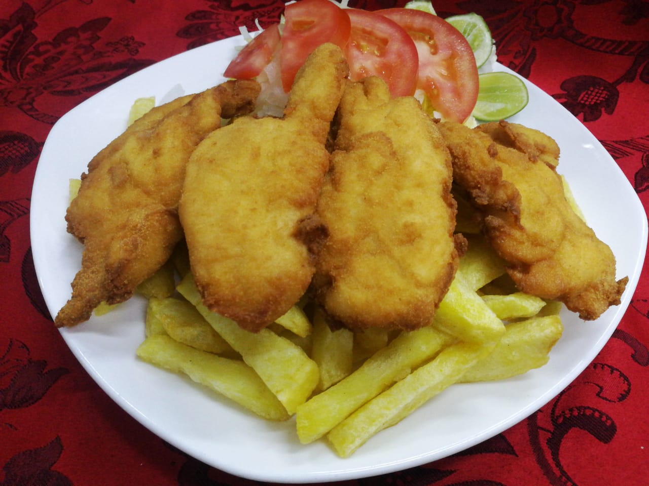 Pollo apanado servido con papas fritas.